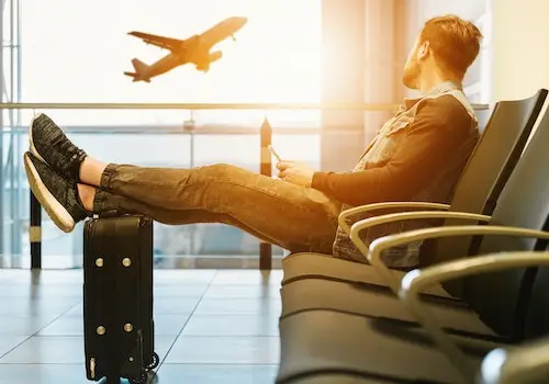 homem sentado no aeroporto com passagens aéreas olha para avião que decola